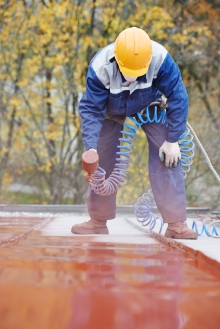Ouvrier à refaire la peinture d'un toit de tôlt